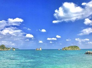 A coastal scene with clear blue water, scattered islands, and a lighthouse in the distance. - Stäy Hotel (Nago)