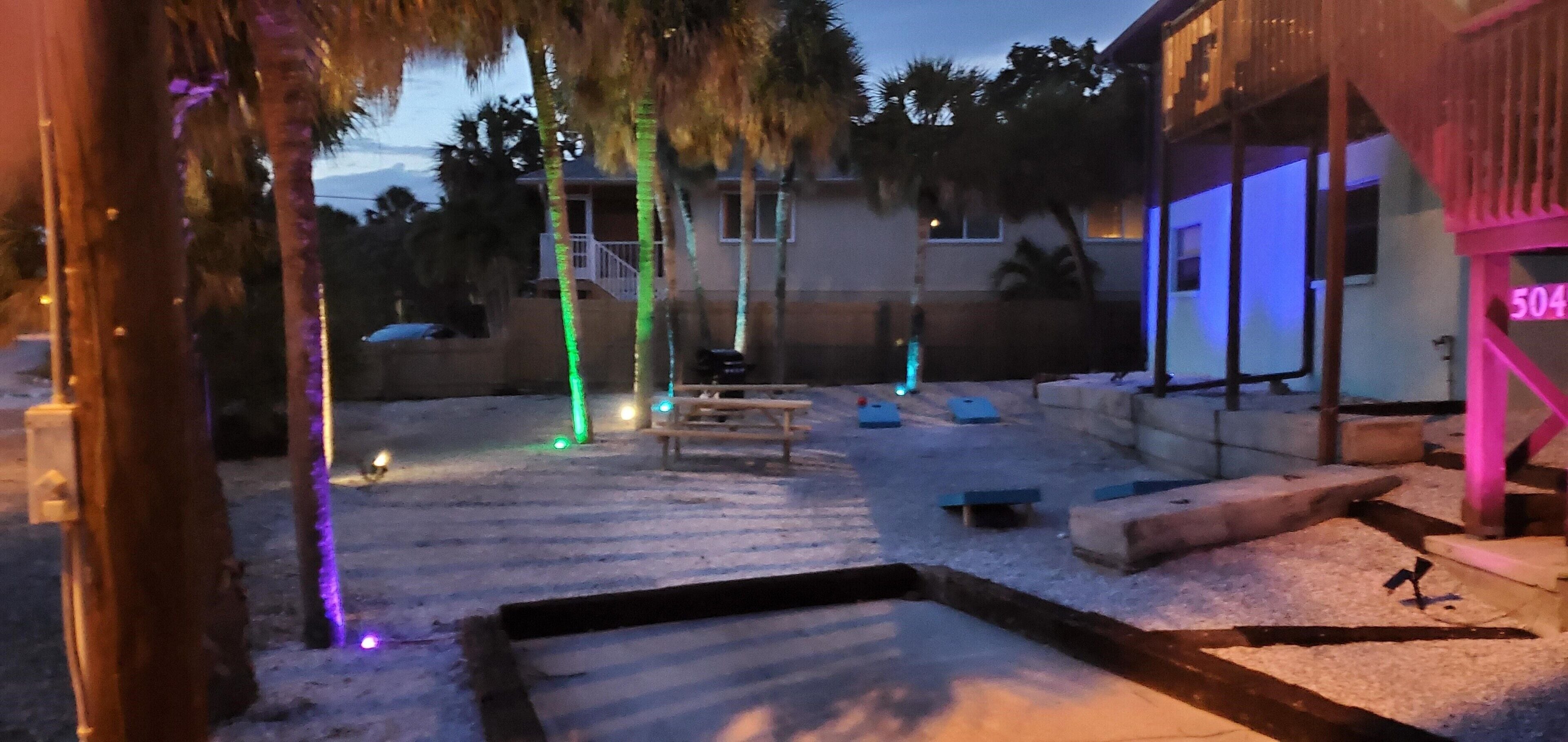 Ein Garten mit Pool, Palmen und einem Haus mit Neonreklame.