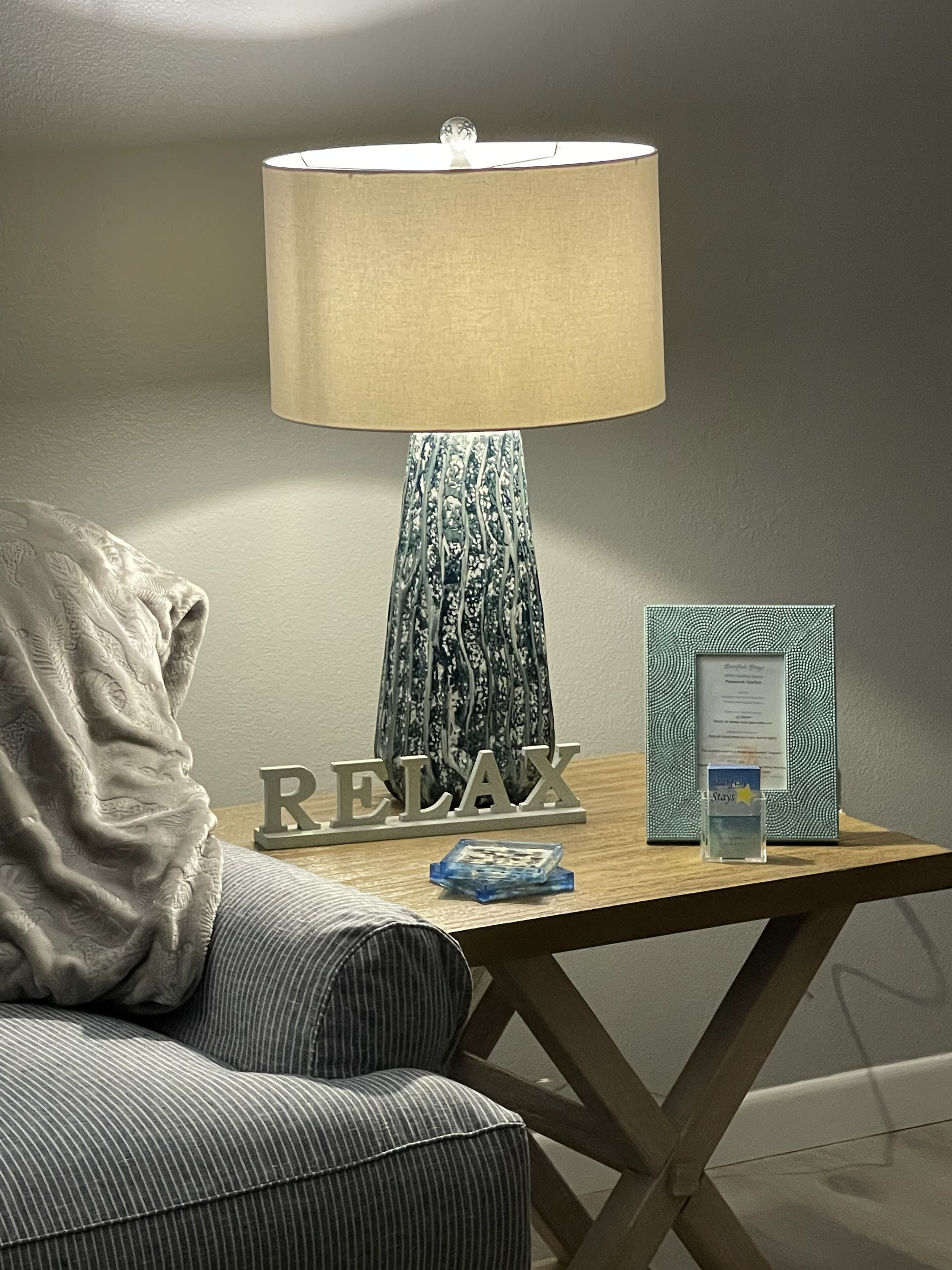 A bedside table with a lamp, a framed menu, and a pillow.