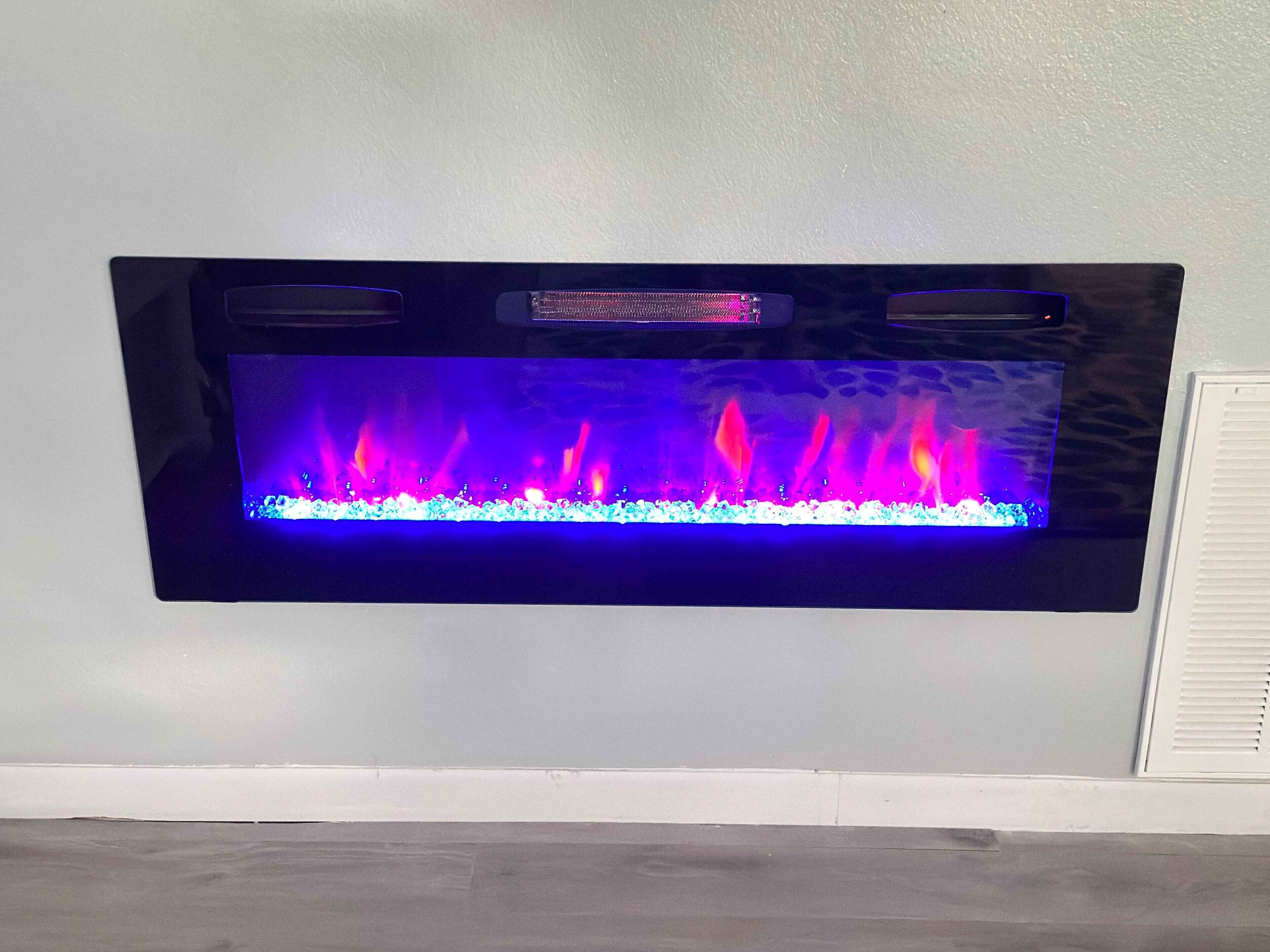 Una chimenea empotrada en la pared, con fuego a la vista y panel de control.