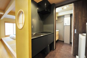 A compact kitchen with a black countertop, a built-in oven, and a small sink. - Senlax Inn Osaka (Osaka)