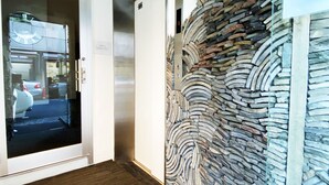 A hallway with a stone wall, a door with a glass panel, and a wooden floor. - Senlax Inn Osaka (Osaka)
