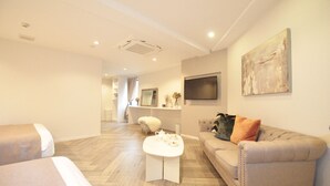A modern living room with a sofa, a coffee table, and a TV mounted on the wall. - Senlax Inn Osaka (Osaka)