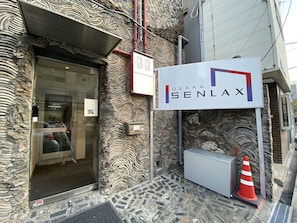A building entrance with a stone facade, a glass door, and a sign reading "OSAKA SENLAX".