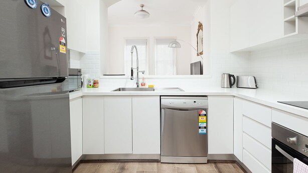 A modern kitchen with white cabinetry, a stainless steel refrigerator, a dishwasher, and a toaster.