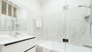 A modern bathroom with a glass-enclosed shower, a white vanity with a mirror, and a bathtub.