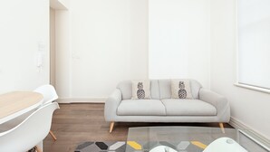A modern living room with a grey sofa, a white coffee table, and a white chair.