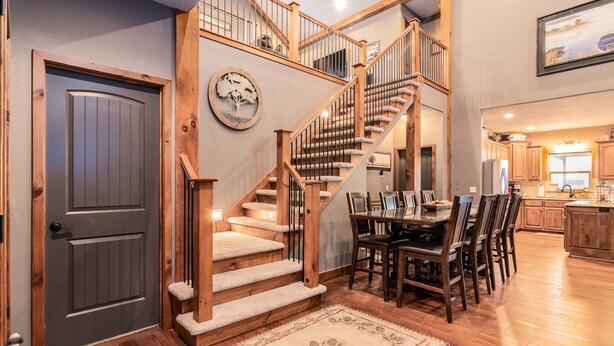A spacious kitchen with wooden cabinets, a dining area with a table and chairs, and a staircase with a wooden railing. - THEATER/GAME ROOM w/100” Screen!! Pool Table!  Dining Seats 20! 3 Living Areas! (Hollister)