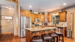 A modern kitchen with wooden cabinets, stainless steel appliances, and a granite countertop. - THEATER/GAME ROOM w/100” Screen!! Pool Table!  Dining Seats 20! 3 Living Areas! (Hollister)