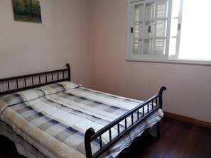 Cozy bedroom with a single bed, a checkered quilt, and a painting above.
