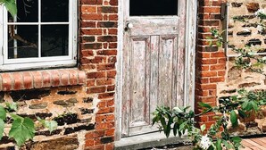 A rustic brick building with a weathered wooden door and a window. - The Kings Stables at Burnside (Burnside)