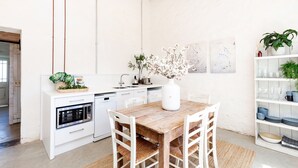 A modern kitchen with white cabinetry, a wooden dining table, and a ceiling fan. - The Kings Stables at Burnside (Burnside)