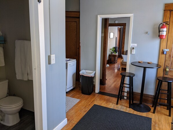 A compact kitchen with a refrigerator, a sink, and a small dining area with stools.