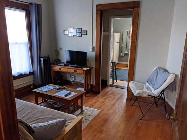 A cozy living room with a wooden desk, a television, and a comfortable chair.