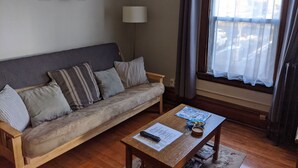 A living room with a sofa, a coffee table with a remote control, papers, and a bowl. - Great Uptown Apartment! Great Location! (Minneapolis)