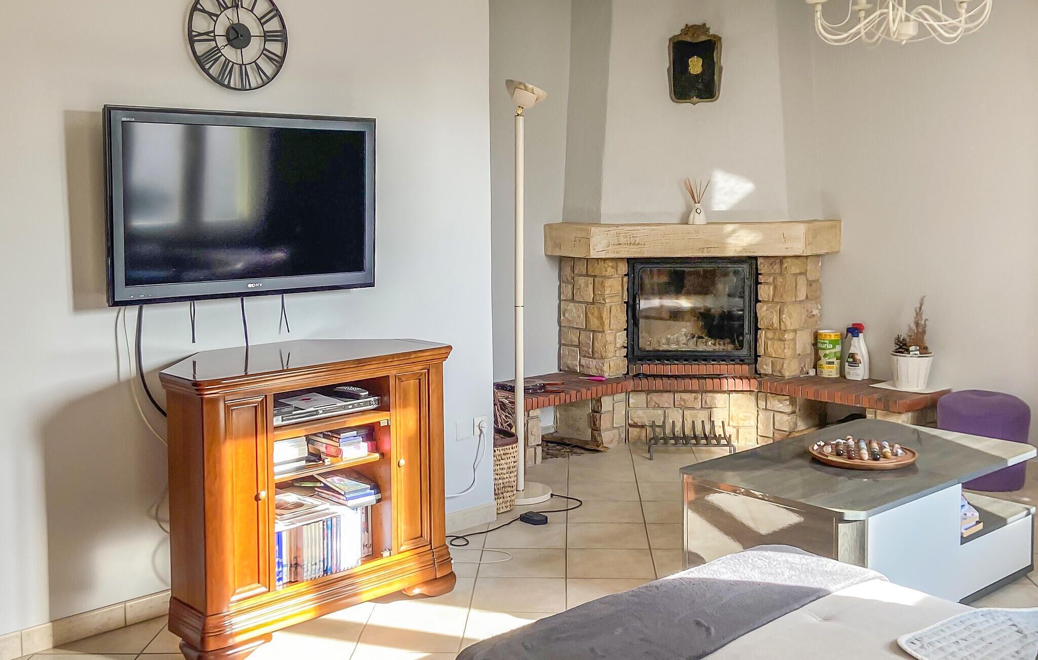 A living room with a flat-screen TV, a wooden bookshelf, a stone fireplace, and a modern coffee table.