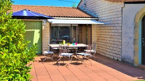 A patio with a table and chairs, a blue umbrella, and a brick wall. - Stunning home in Orange (Orange)