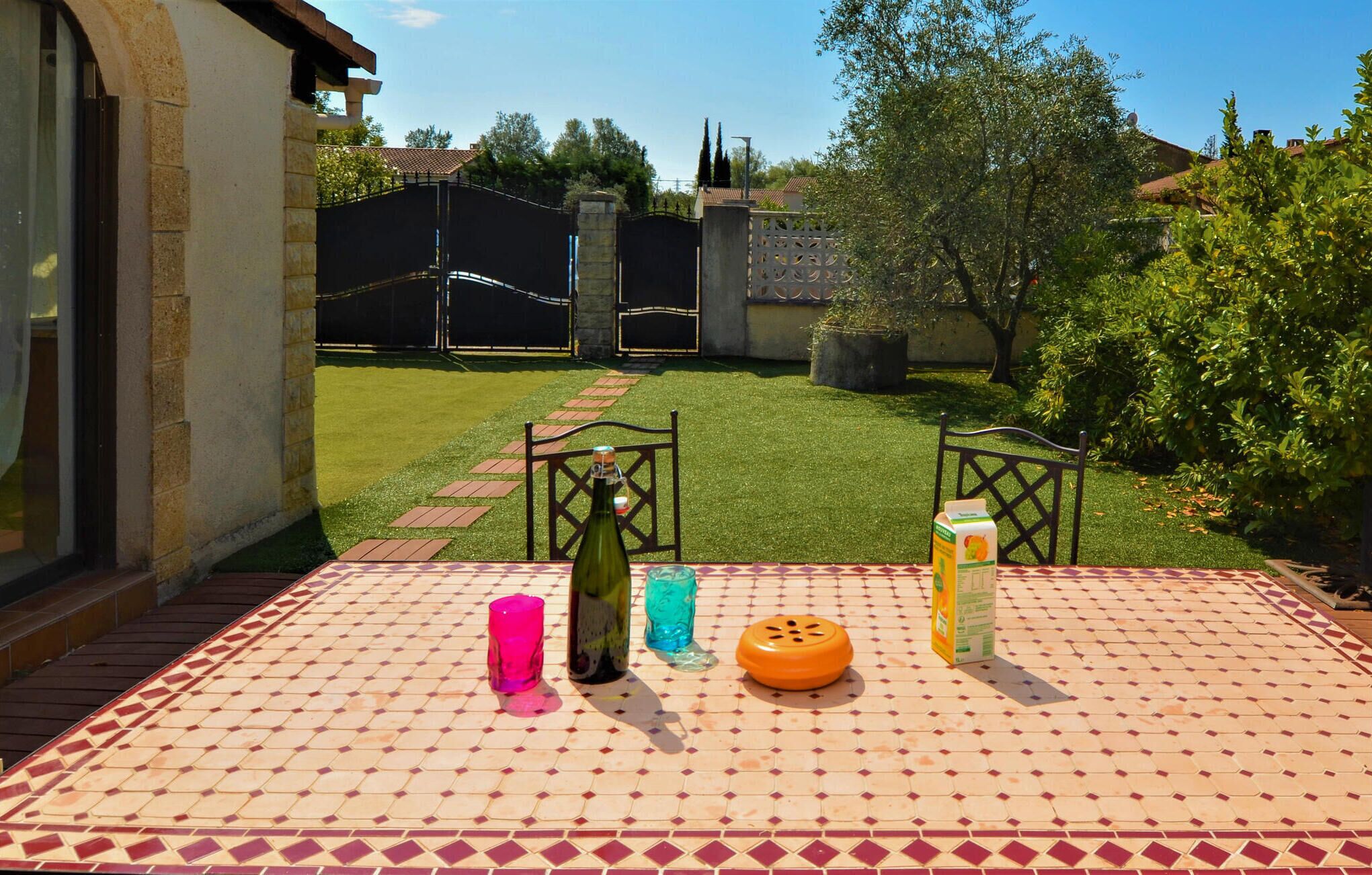 Un patio con un tavolo apparecchiato per due, con una bottiglia, un bicchiere e un succo di cartone.