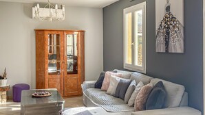 A living room with a grey sofa, a wooden cabinet, and a glass coffee table. - Stunning home in Orange (Orange)