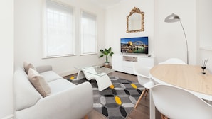 A modern living room with a sofa, coffee table, TV, and dining area. - Stunning Sydney Home 8 (Millers Point)