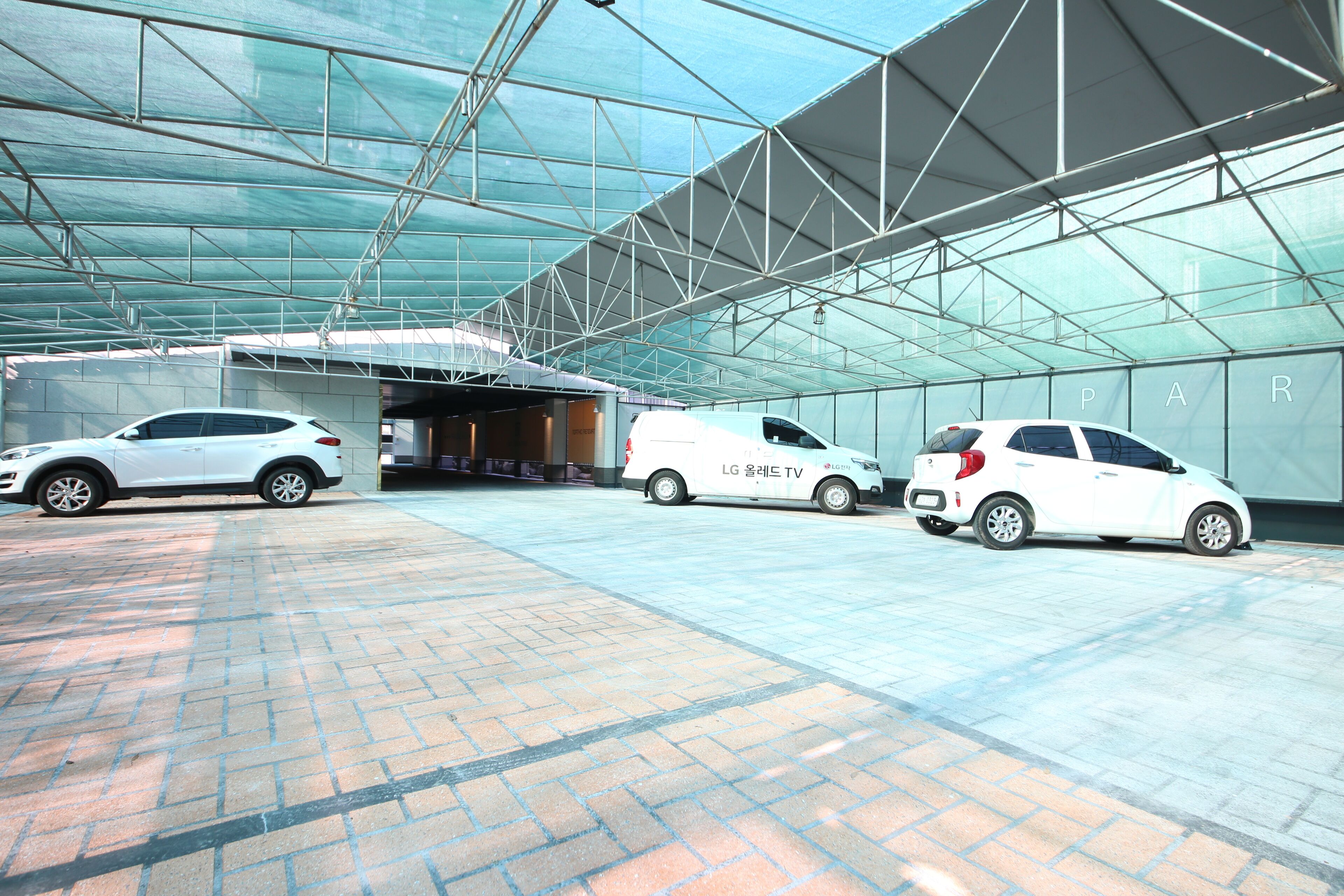 A modern building with a glass facade and a covered parking area.
