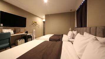 A hotel room with two beds, a desk, a television, and a chair.