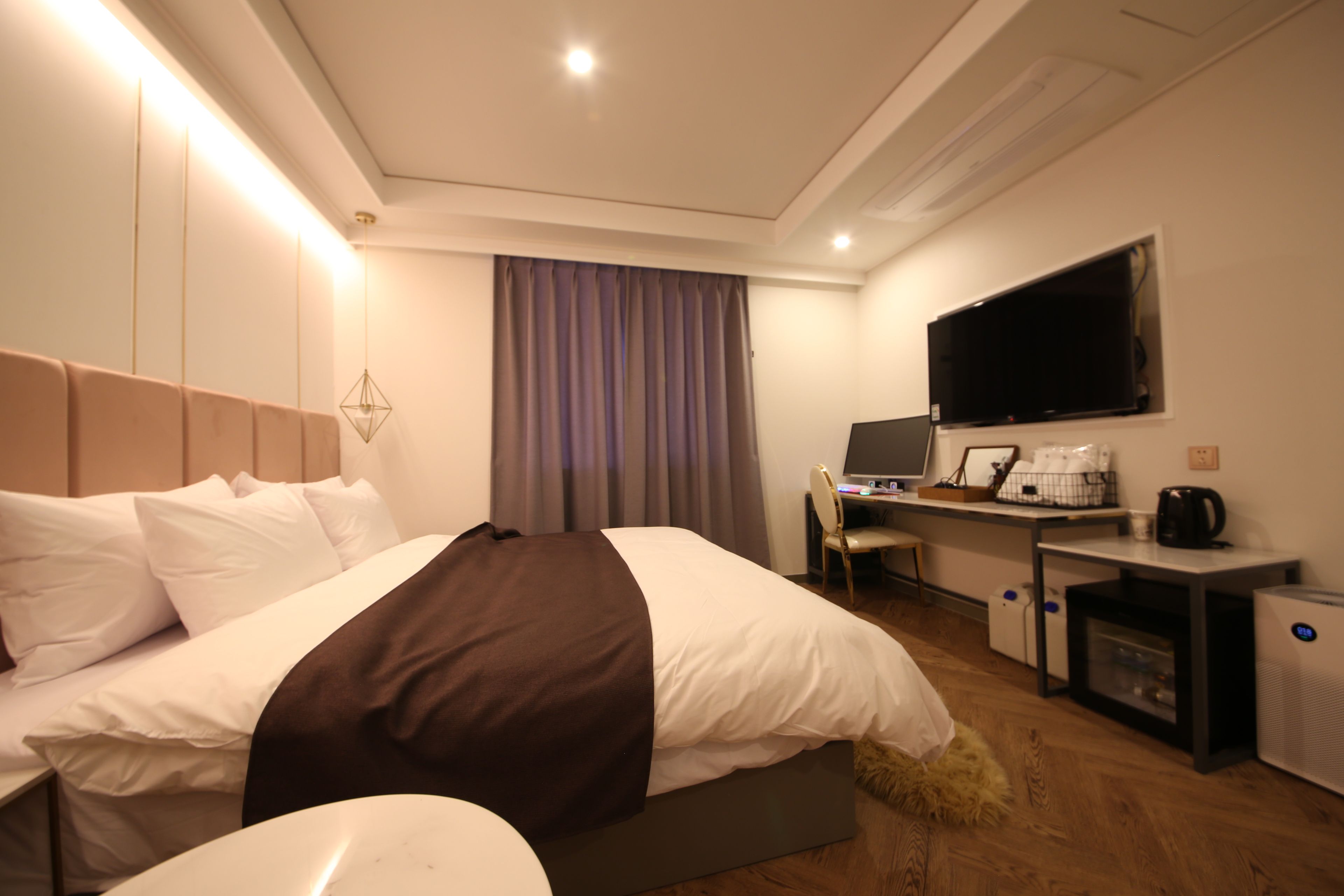 Una habitación de hotel con cama, escritorio, televisor y cafetera.
