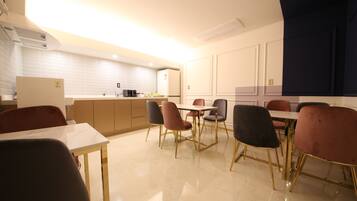 A modern kitchen with white cabinets, a central island, and a dining area with chairs and a table.