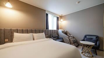 Una habitación de hotel con una cama grande, una zona de estar con sofá y sillones, y una mesita.