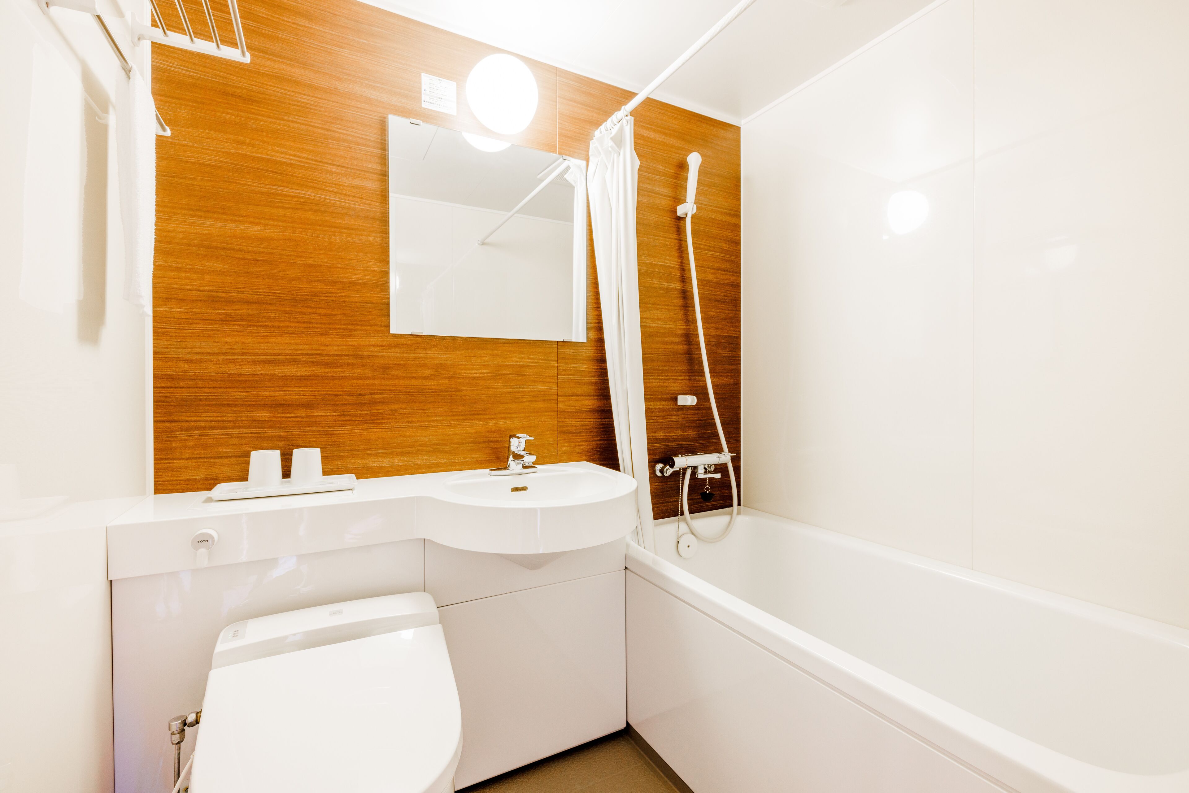 A modern bathroom with a wooden vanity, a white sink, a toilet, and a bathtub.