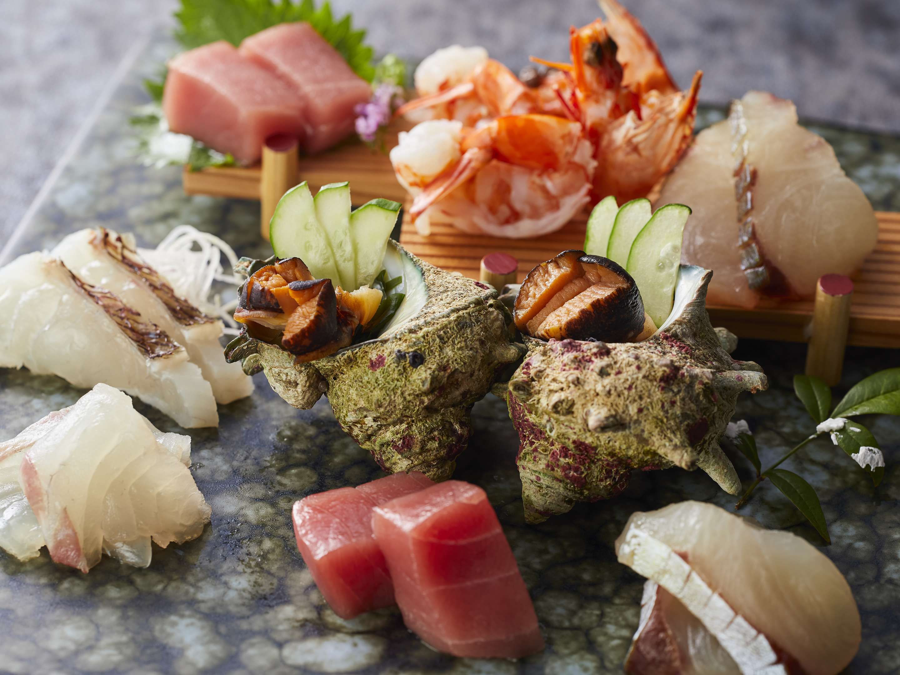 Une sélection de sushis et de sashimis présentés sur une planche en bois.