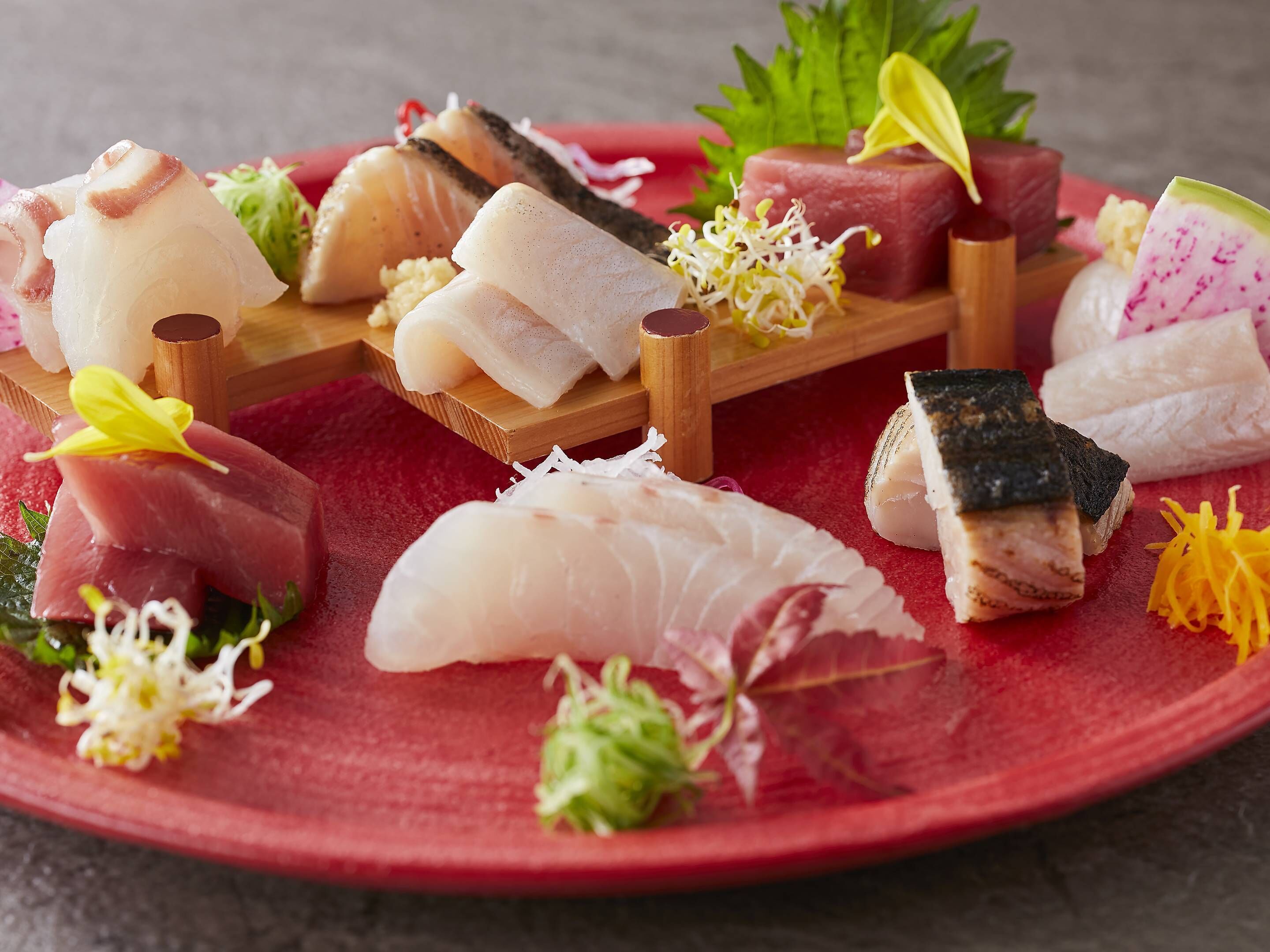 A variety of sashimi and sushi on a wooden serving board.