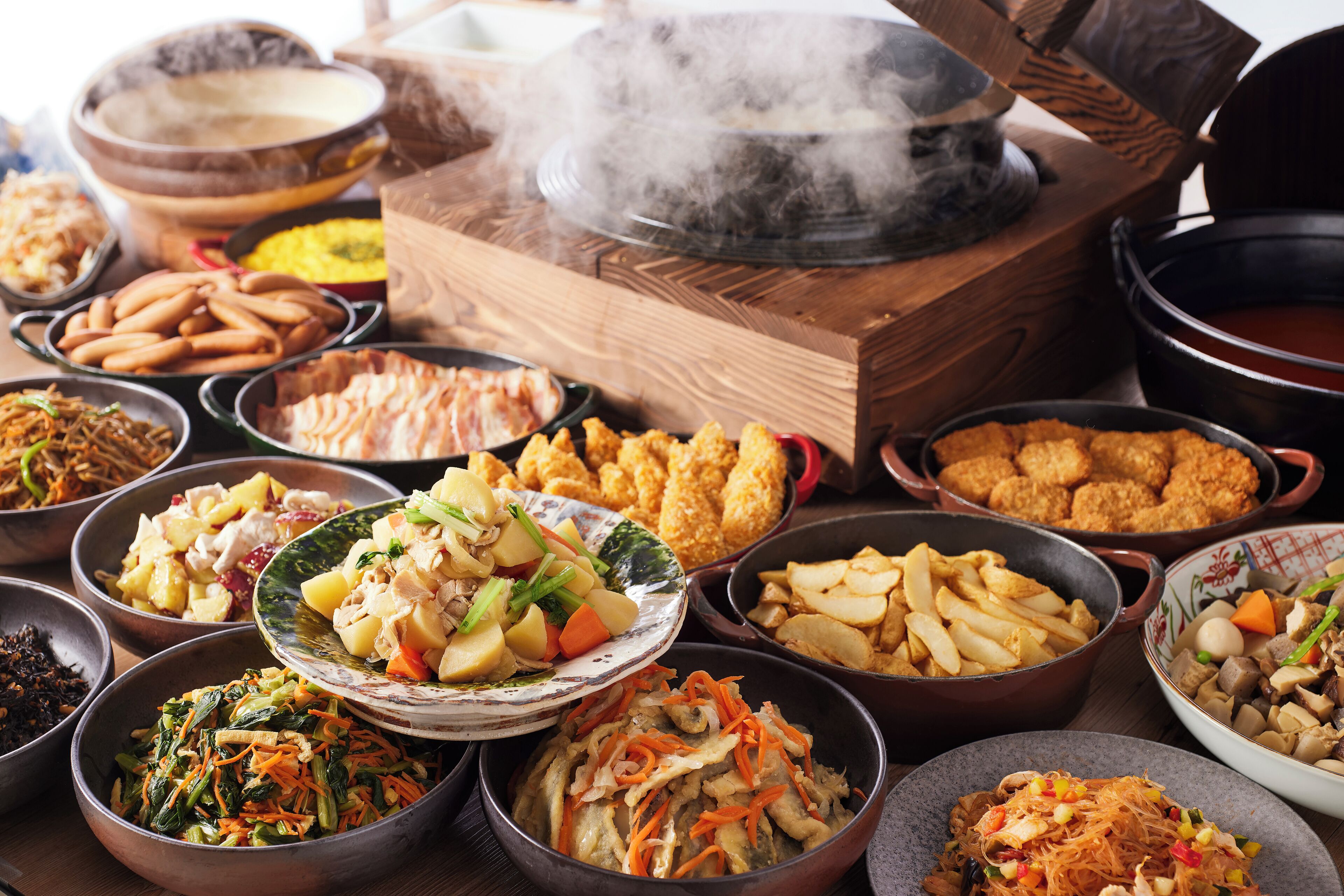 A variety of dishes arranged on a table, including fried items, salads, and other food options.