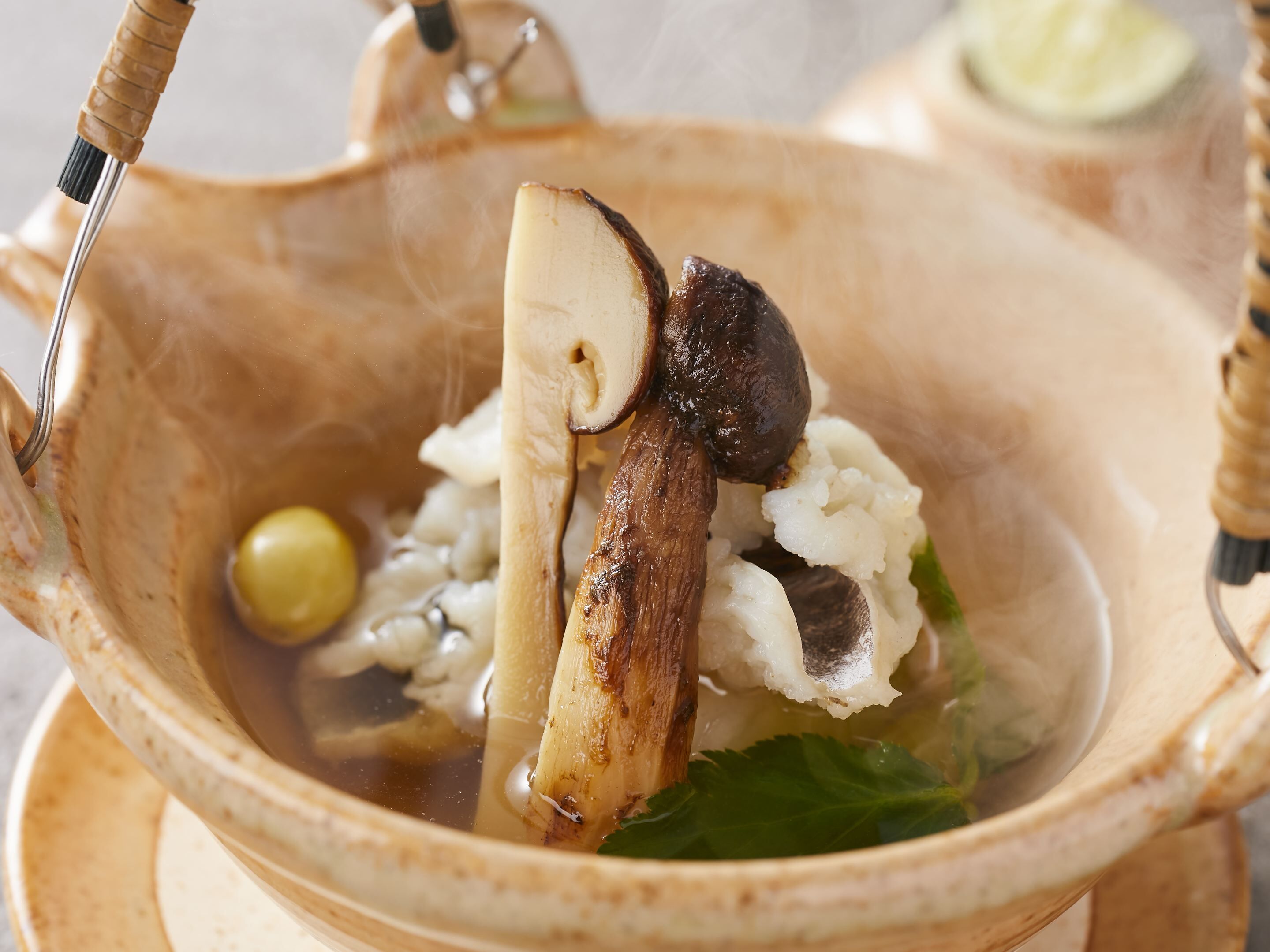 A ceramic bowl with a handle, containing a white substance, possibly rice, and a mushroom.