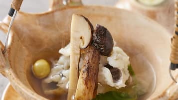 A ceramic bowl with a handle, containing a white substance, possibly rice, and a mushroom.