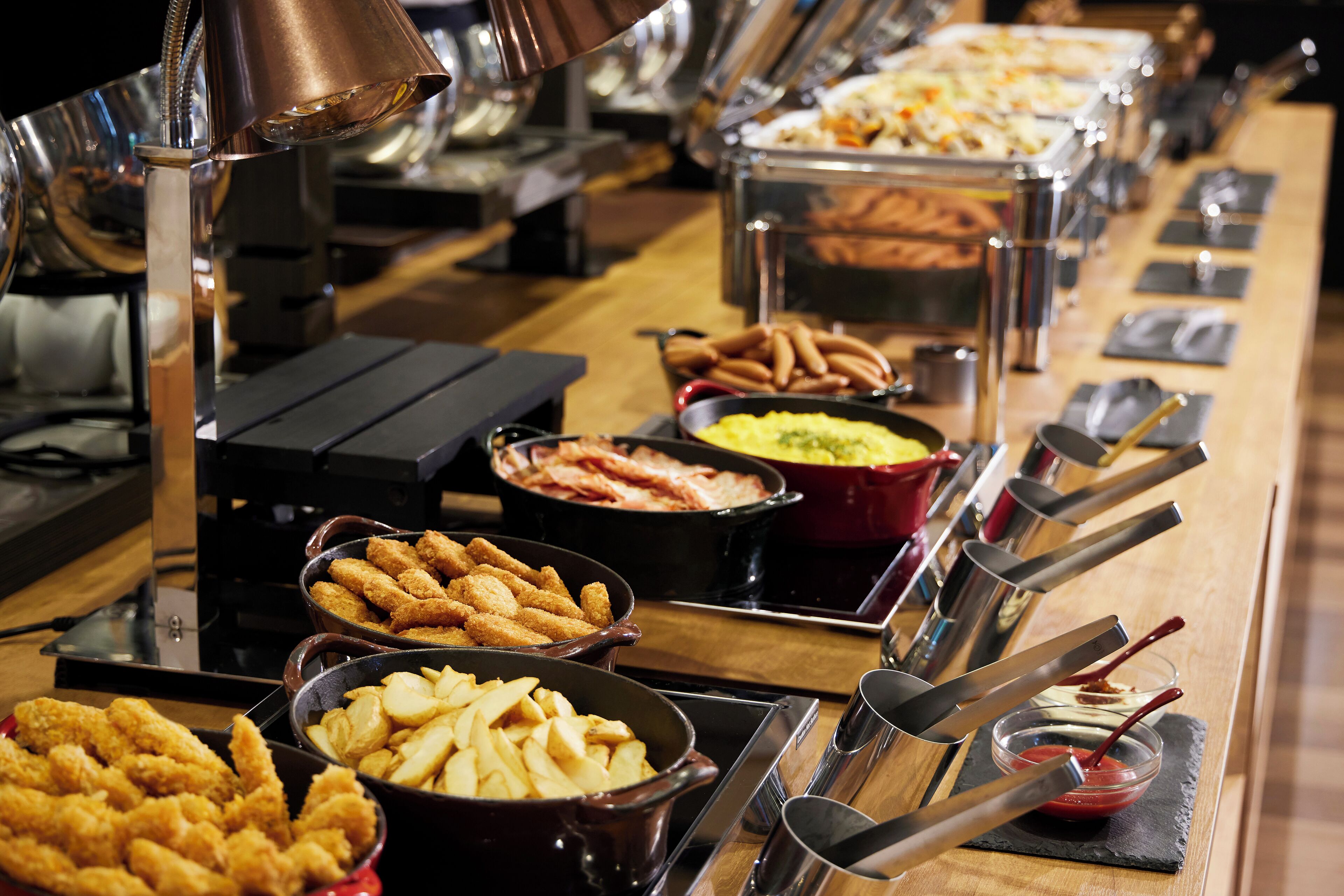 A buffet with various food items including fried chicken, French fries, and other dishes.