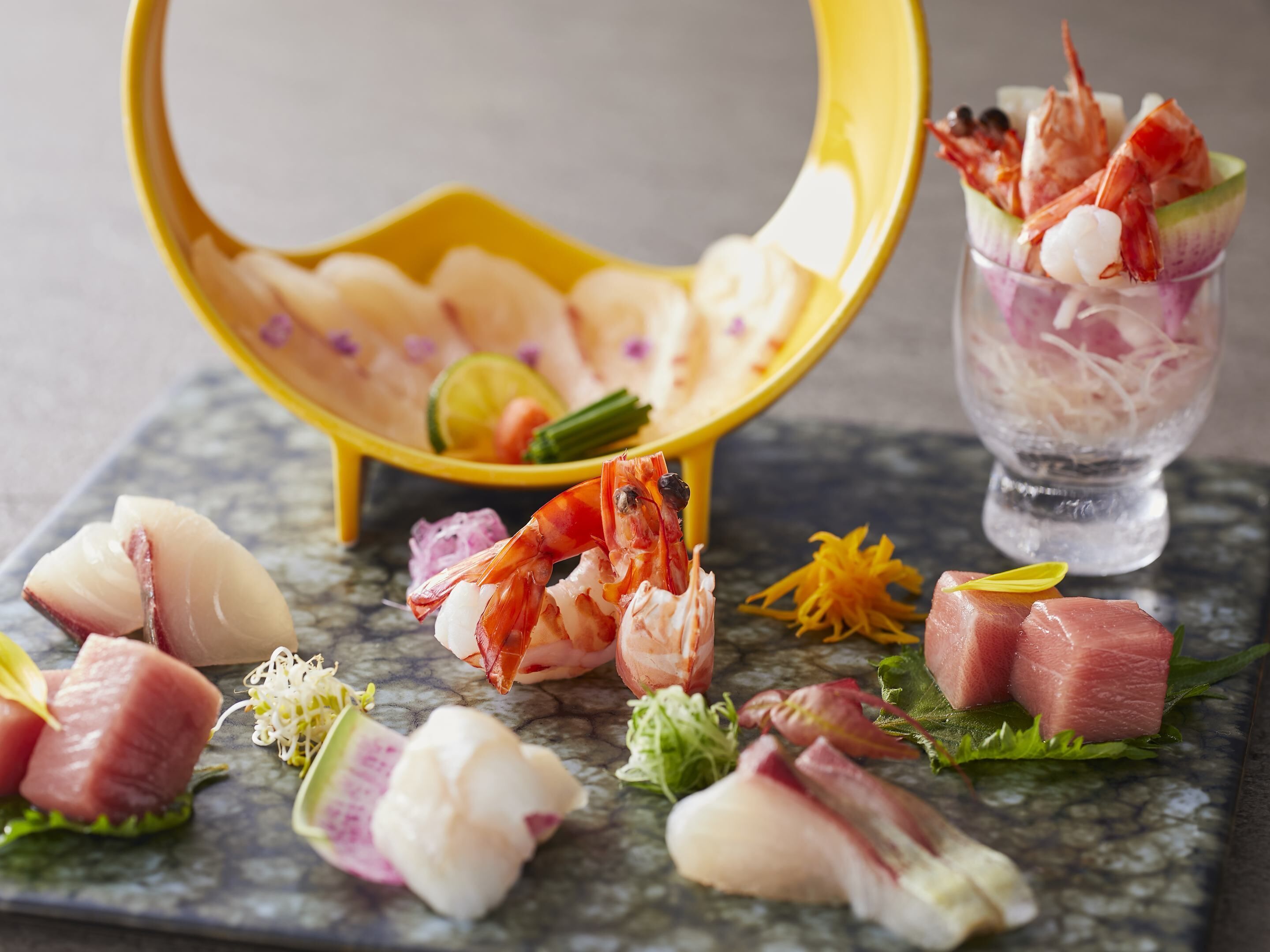 A variety of seafood arranged on a marble table, including shrimp, fish, and possibly sashimi.