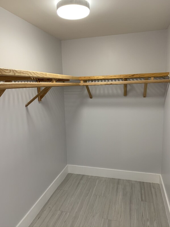 A room with a built-in wooden drying rack, grey walls, and a grey wooden floor.
