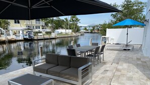 Um pátio externo com conjunto de jantar, sofá e mesa.