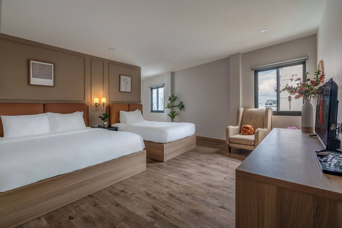 Une chambre d’hôtel avec deux lits, un bureau, une chaise, une télévision et une fenêtre donnant sur un beau paysage.