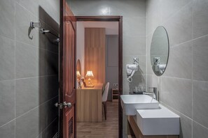 Ein modernes Badezimmer mit Holztür, Waschbecken in Weiß, Spiegel und Lampe.