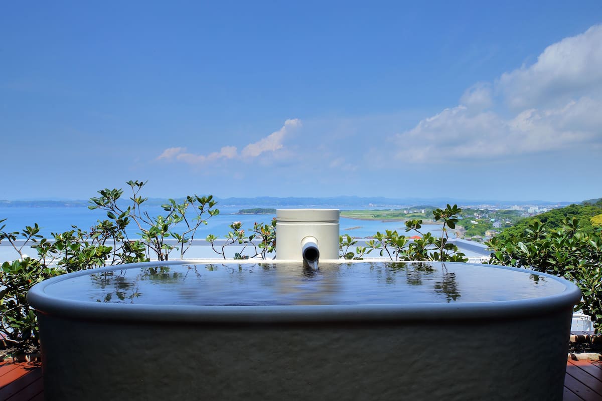 A hot tub with a view of the sea and distant mountains.