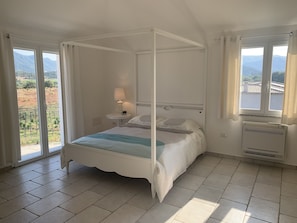 Ein Himmelbett mit Blick ins Freie durch große Fenster.