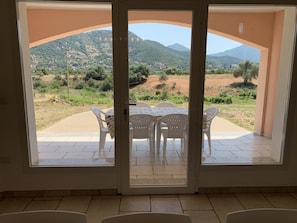 Ein Zimmer mit Blick auf eine gebirgige Landschaft durch eine Glastür.