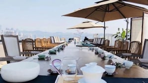 A dining area with a long table, chairs, and umbrellas. - Lingshang 1941 Inn (Chongqing)