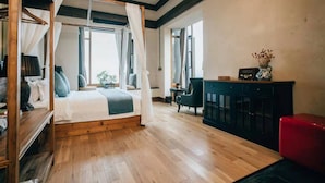 A bedroom with a four-poster bed, a wooden floor, a dark-colored cabinet, and a red chair. - Lingshang 1941 Inn (Chongqing)