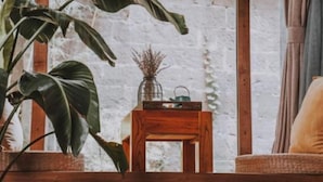 A cozy room with a large window, a wooden table with a vase, and a wicker chair. - Lingshang 1941 Inn (Chongqing)