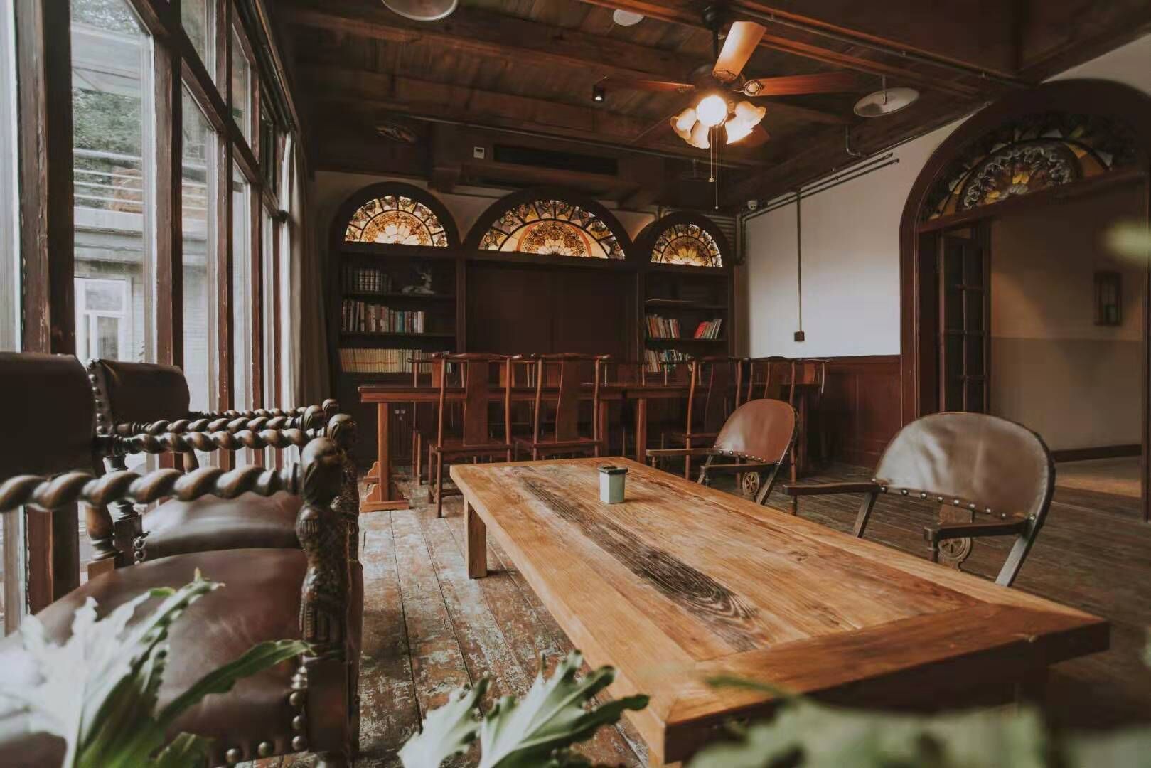 A cozy room with a wooden table, leather chairs, and a bookshelf filled with books.
