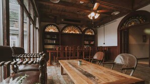 A cozy room with a wooden table, leather chairs, and a bookshelf filled with books. - Lingshang 1941 Inn (Chongqing)