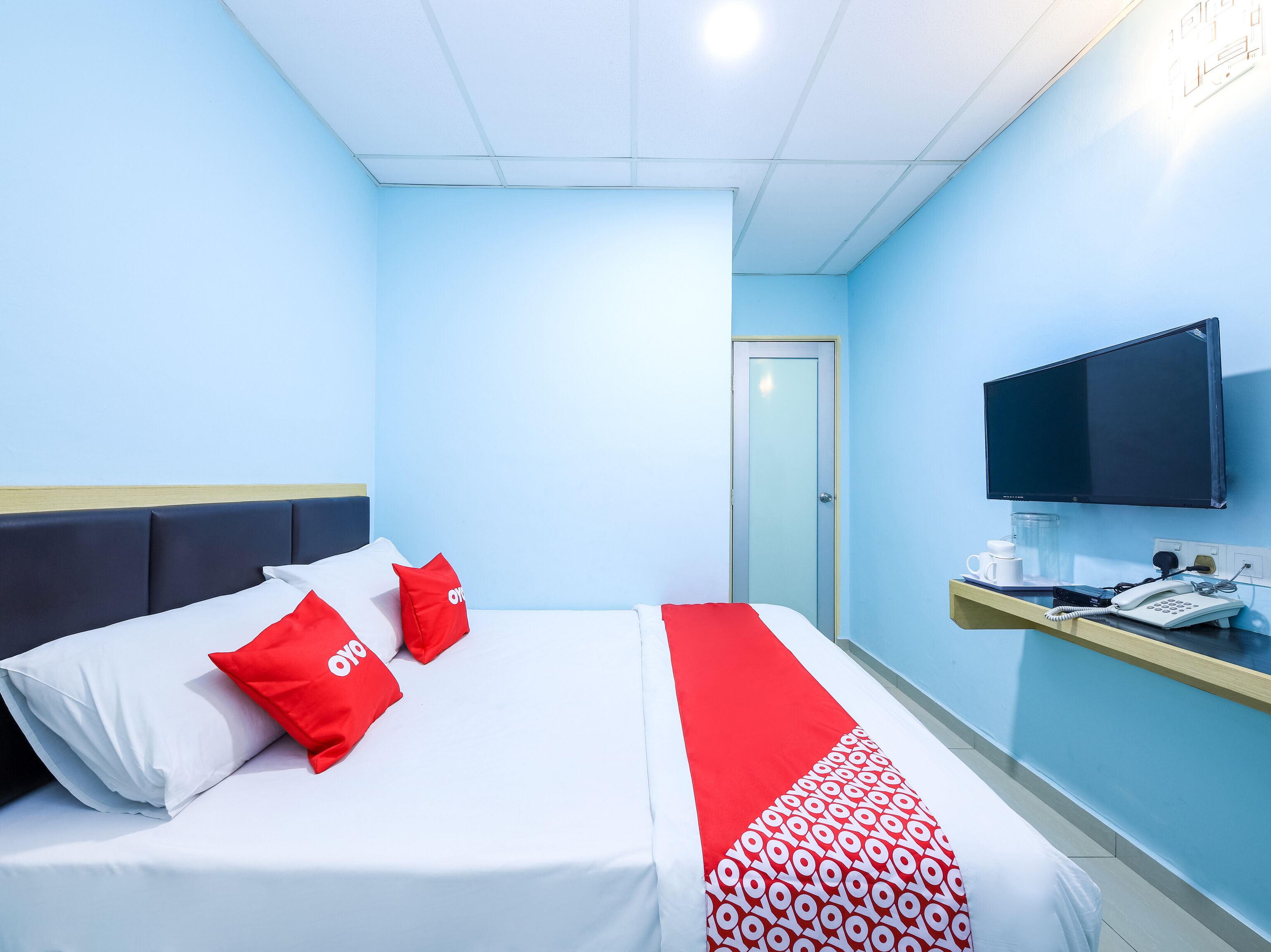 Habitación de hotel con cama, televisión, teléfono y cafetera.